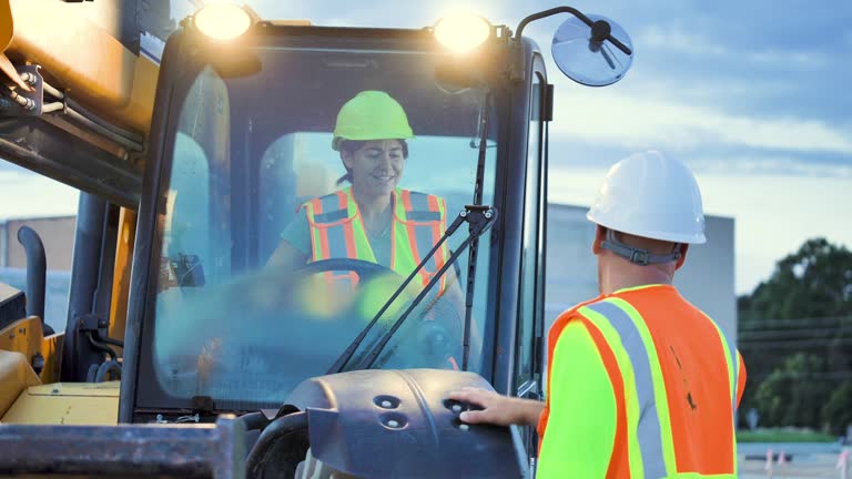 Multiracial workers at job site with construction vehicle