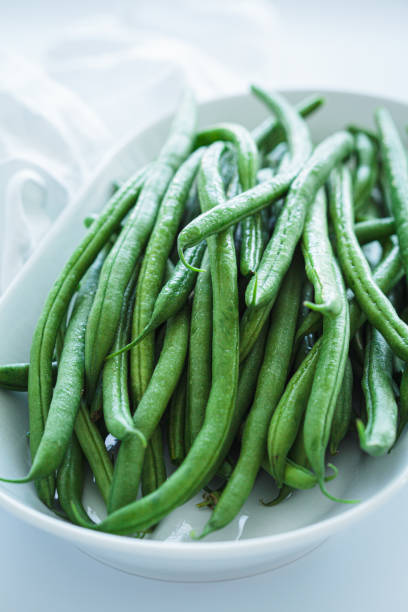 istock Raw fresh green beans on white plate, white background. 1906222521