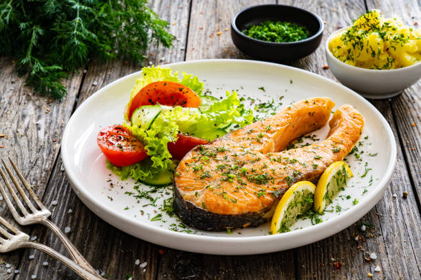 istock Seared salmon with fresh vegetables on wooden table 1906242775