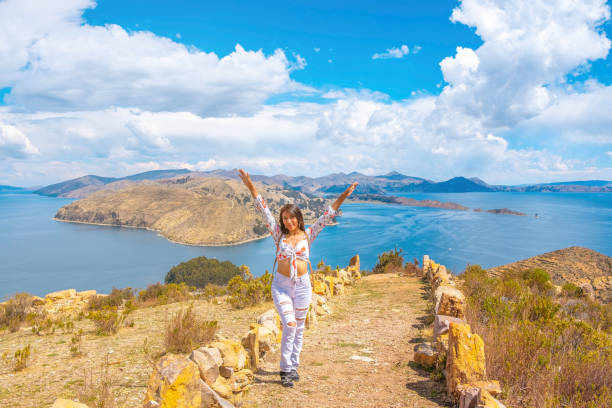 glückliche und entspannte lateinamerikanerin mit erhobenen armen im urlaub auf der isla del sol am ufer des titicacasees in bolivien - bolivia copacabana bolivian ethnicity lake titicaca stock-fotos und bilder