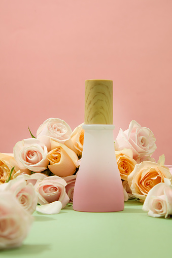 Pink background with roses and a bottle of homemade cosmetics on display. Roses contain phytochemicals such as nerol, geraniol and citronellol that help fight many germs and bacteria.