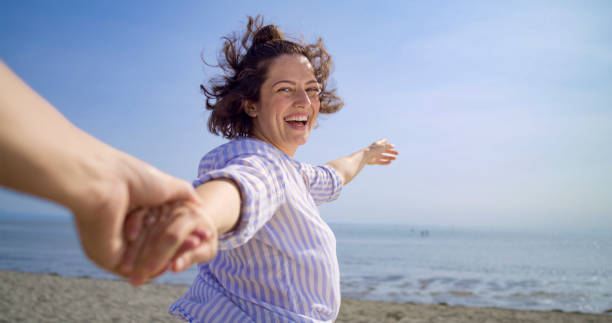 istock Woman holding man's hand on beach 1906326000