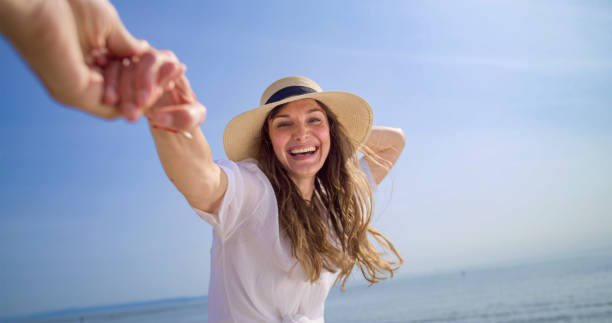 istock Woman holding man's hand on beach 1906326025