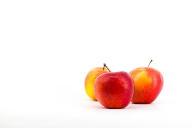 The image captures the vibrant contrast of red apples against a pristine white backdrop. The vivid red hue of the apples stands out, evoking freshness and allure. The simplicity and elegance of the white background enhance the natural beauty of the composition. This photo radiates freshness and health.
