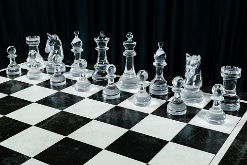 Chessboard with crystal chess pieces on a dark background.