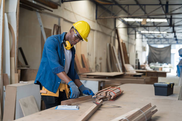 istock Male carpenter working in wood processing plants. Black male carpenter working at wood workshop. Concept of wood industrial factory 1906383076