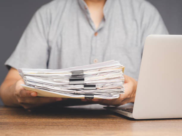 istock Businessman holding a pile of documents while sitting at the table 1906433972