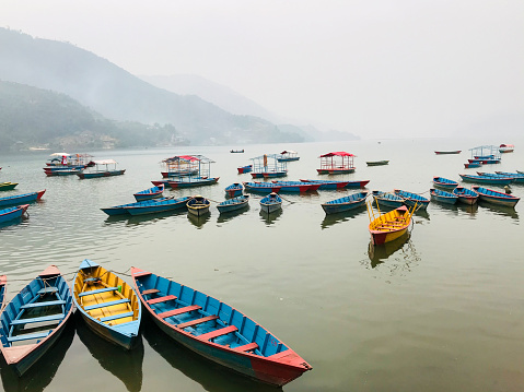 Boats at Phewa Fewa Lake in Pokhara, Nepal.T he Boats with different colors,The blue sky reflection in the water.view from Phewa Lake.