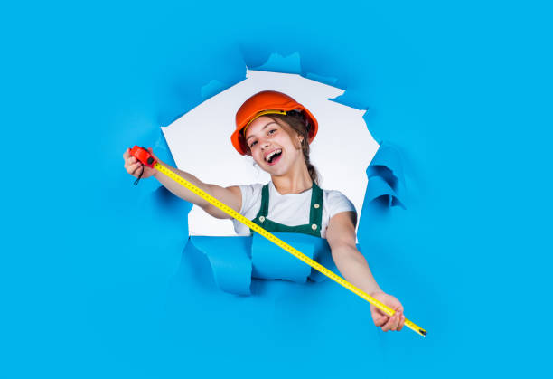 istock cheerful child laborer using building uniform and tape measure, measurement 1906457087