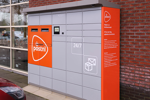 PostNL Dutch postal service, automatic package pickup and deliver point locker system. 24 7 accessible lockers for packages and mail with orange company logo