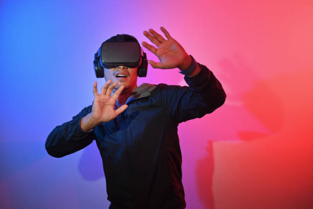 istock Excited and amazed young Asian man experiencing virtual reality in VR headset 1906478207