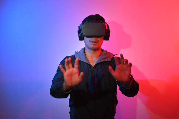 istock Smiling man wearing VR headset feeling excited and trying to touch something with hands. 1906478321