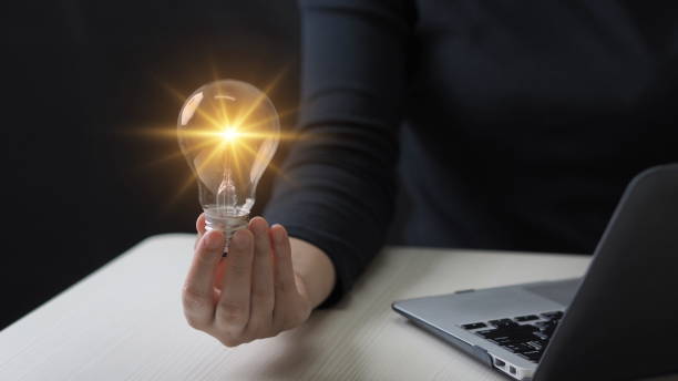 istock Idea innovation and inspiration concept. Hand of man holding illuminated light bulb, concept creativity with bulbs that shine glitter. Inspiration of ideas for sustainable business development. 1906488810