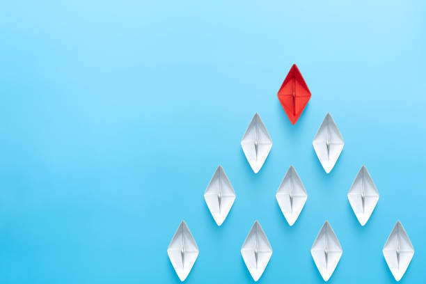 istock Leadership concept. Red leader paper ship leading among white on blue background. copy space 1906488814