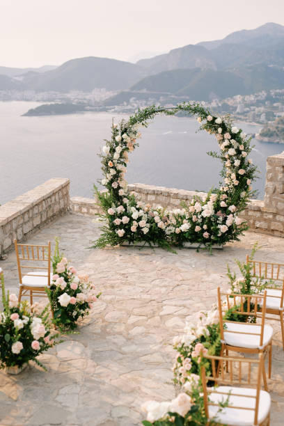 istock Chairs decorated with flowers stand in front of a round wedding arch on an observation deck over the sea 1906548045