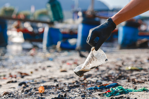 Close up shot of man picking up plastic cup at the beach