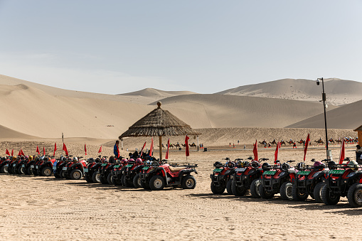 Dunhuang, China – July 17, 2018: A row of parked all-terrain vehicles in a sun-baked in the Kumtag Desert