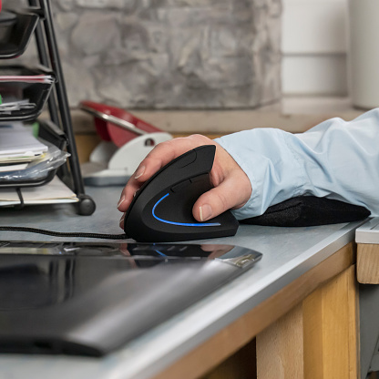 A man sitting at a workspace desk, holding a computer mouse