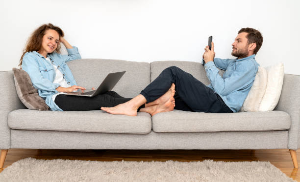 istock Woman and man relax on sofa and using their digital portable information devices. 1906609764