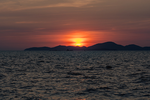 Beautiful golden sunset over the sea behind mountains in background and have light reflection on the water as the sunset.