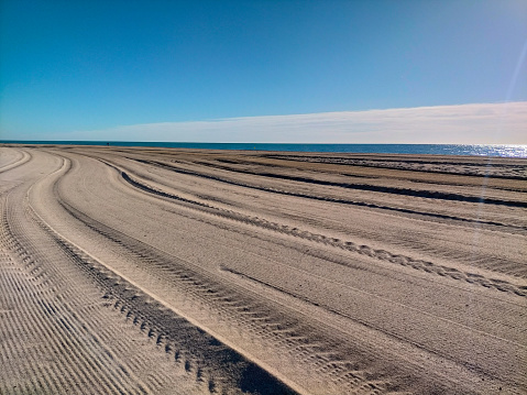 Escena de una playa del mar Mediterráneo con arena recién peinada con el tractor que limpia la arena de la playa. Fondo del mar. Playa de Vilassar de Mar-Barcelona. photo