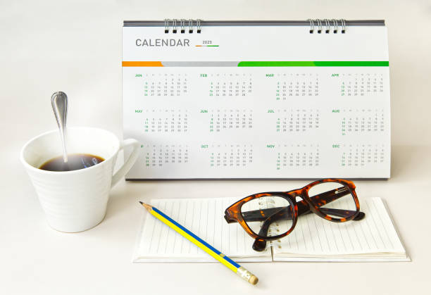istock Desk calendar 12 months year 2025 with notepad eyeglasses pencil and hot coffee, object background 1906667787