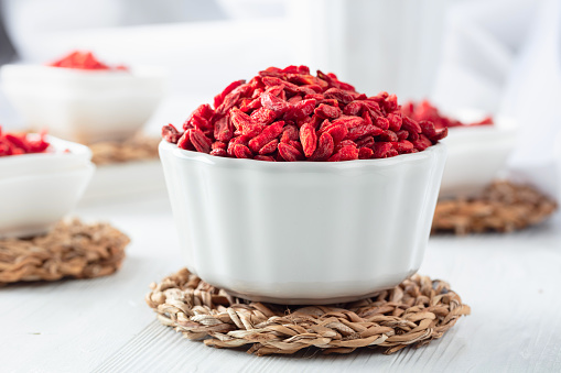Dried goji berries on a white wooden table.