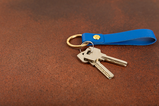 Leather keychain with a key ring on  background. Concepts for real estate and moving home or renting property. Buying a property. Mock-up keychain.Copy space.