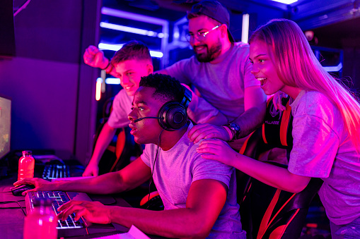 A dynamic image of a black man deeply focused on playing a video game at an eSports competition, surrounded by a cheering multiracial crowd, embodying the excitement and camaraderie of the gaming community