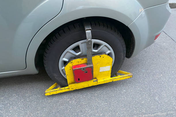parking penalty fee or penalty. A Wheel Clamp Boot On Wheel of Car. Illegal parking on wrong street place parking penalty fee or penalty. A Wheel Clamp Boot On Wheel of Car. Illegal parking on wrong street place car boot stock pictures, royalty-free photos & images
