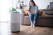 Young woman in living room setting up home air purifier.