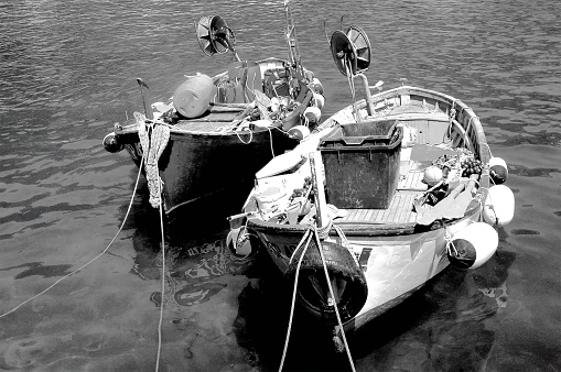 This photograph shows two boats moored at a dock, with the boat on the left bearing the name \