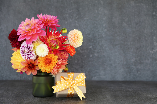 Closeup of colorful flowers. Moody autumn wedding or birthday bouquet. Pink and burgundy dahlia, cosmos and aster flowers. Amaranthus and eucalyptus foliage, selective focus. White wall.