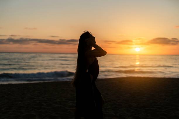 istock Young woman posing on a sandy beach at sunset 1906765167