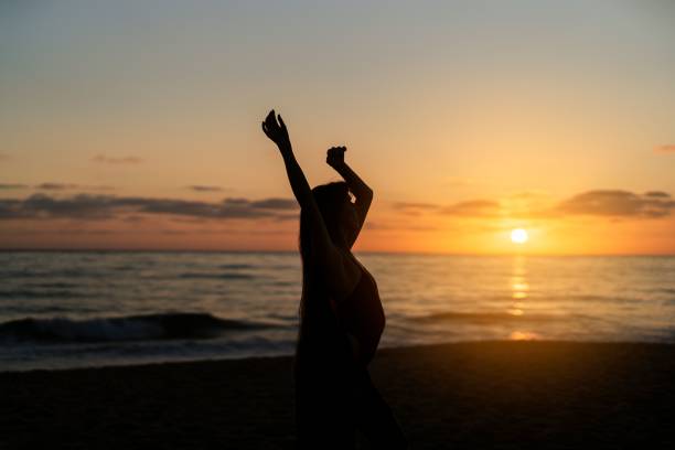 Young woman posing on a sandy beach at sunset