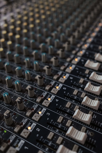 A vertical closeup of an analog audio mixer in a studio