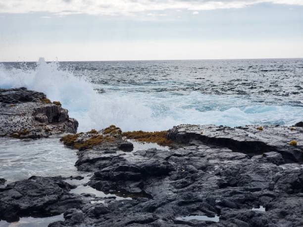 istock Scenic view of a wave crashing onto a rocky cliff 1906770909