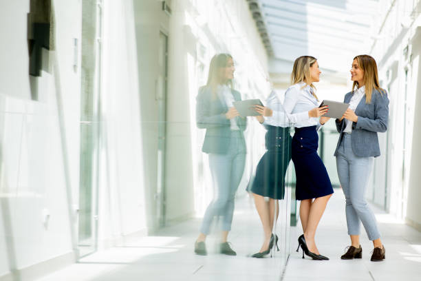 istock Two young business women with digital tablet in the office hallway 1906771507
