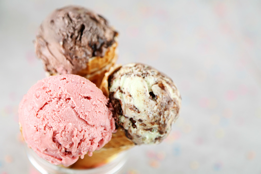 Ripple (vanilla raspberry or strawberry) ice cream  scooped out of a container with a utensil.