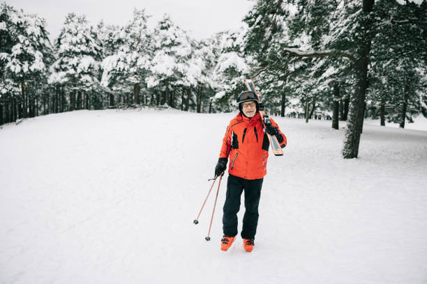 A skier takes a selfie on the ski slope. The view from the skier's phone.  He is wearing a white and red ski suit, ski goggles, and a knitted hat.