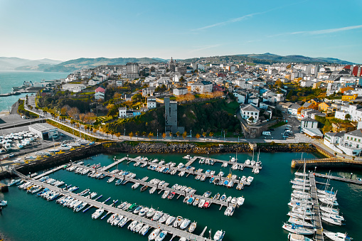 Aerial shot, drone point of view Ribadeo city and harbor with moored nautical vessels during sunny winter day. Province of Lugo in Galicia. Europe, Northern Spain