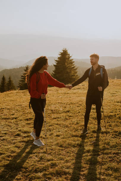 istock Smiling couple walking with backpacks over green hills 1906797155