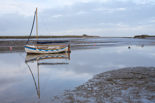Boat with reflections in still water near marshes at Wells-next-the-Sea, Norfolk