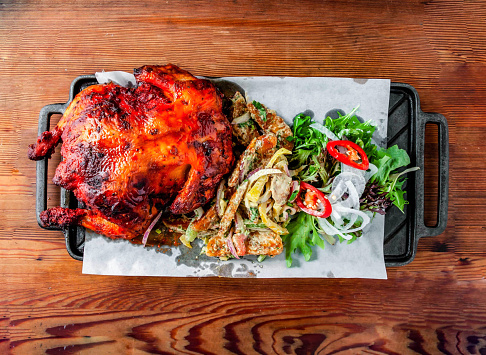 whole grilled chicken with satay, sakura, italian herbs, peri peri, tandoori and salad served wooden board isolated on wooden table top view of hong kong food
