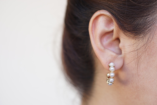 Close up fashionable pearl earring, pendant on woman's ear. Concept, beauty and fashion accessory to decorate on body part. Jewelry and Femininity.