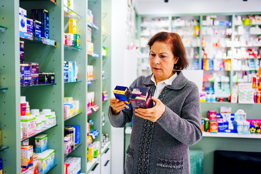 Senior woman reading the back of the medicine bottle at the drugstore