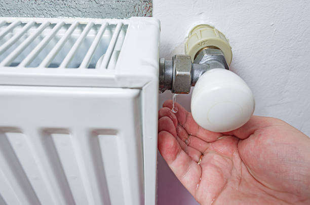 istock Leaking heating radiator. Defective heater. Water pours from the threaded connection of the heating pipe on the men's palm. 1906874694