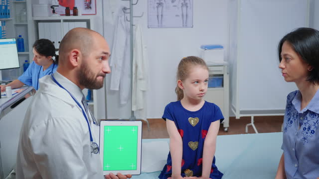 Doctor talking and holding a green screen tablet