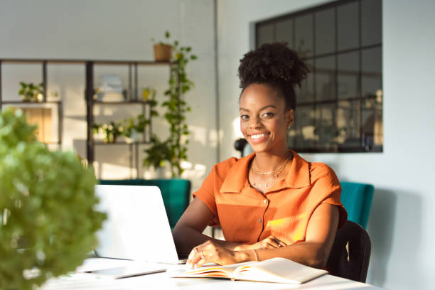 istock Beautiful woman sitting in an office and smiling at camera 1906896521