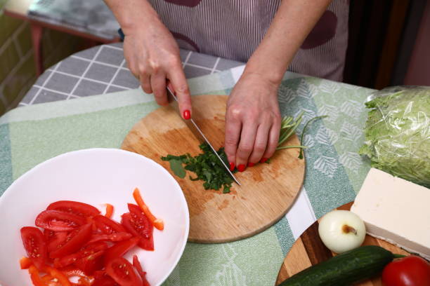 istock Woman cutting fresh arugula in kitchen 1906904399